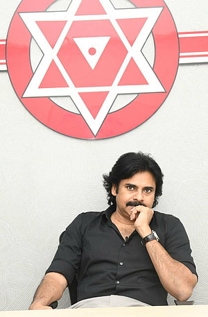 Pawan Kalyan seated in front of the Janasena party emblem with a red and white geometric star design HD phone wallpaper