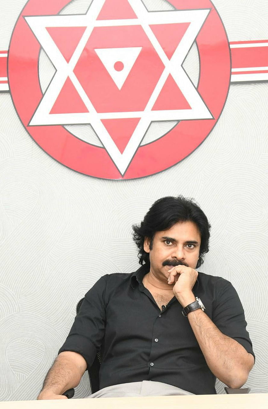 Pawan Kalyan seated in front of the Janasena party emblem with a red and white geometric star design HD phone wallpaper