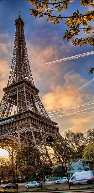 Eiffel Tower in Paris framed by spring blossoms under a dramatic sunset sky HD phone wallpaper