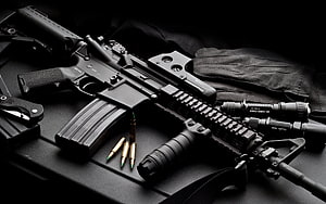 Black Tactical AR-15 Rifle with Ammunition and Gear on Dark Surface HD wallpaper