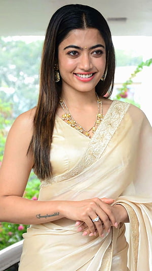 Rashmika Mandanna in an elegant cream silk saree with gold jewelry and a warm smile HD phone wallpaper