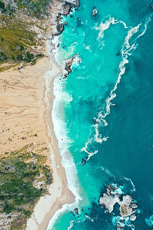 Aerial View of Turquoise Ocean Waves Crashing on a Sandy Coastal Beach with Rocky Outcrops HD phone wallpaper