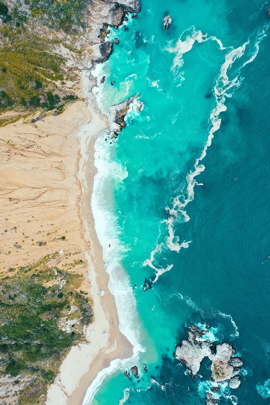 Aerial View of Turquoise Ocean Waves Crashing on a Sandy Coastal Beach with Rocky Outcrops HD phone wallpaper