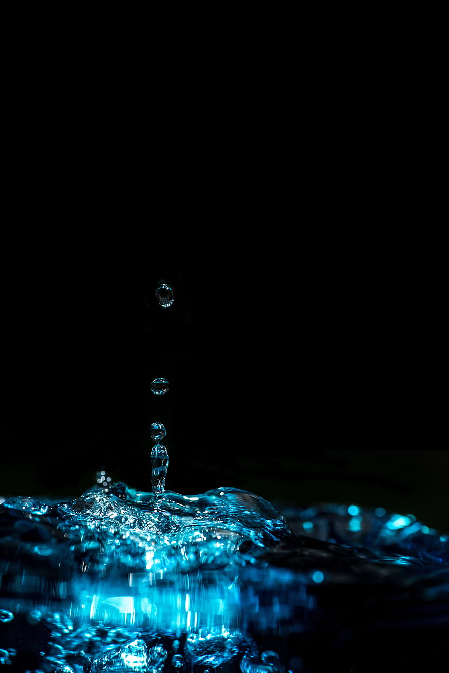 Macro Photography of Water Droplets Falling Into a Glowing Blue Splash Against a Black Background HD phone wallpaper