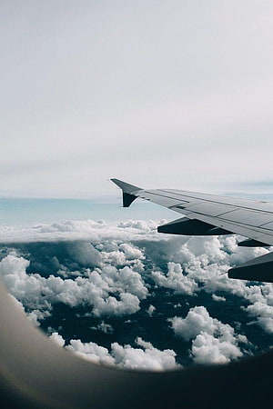 Aerial View of Airplane Wing Above Clouds During Flight HD phone wallpaper