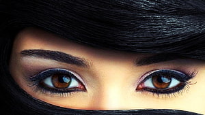 Close-up of expressive brown eyes framed by dark hair and a black hijab HD wallpaper