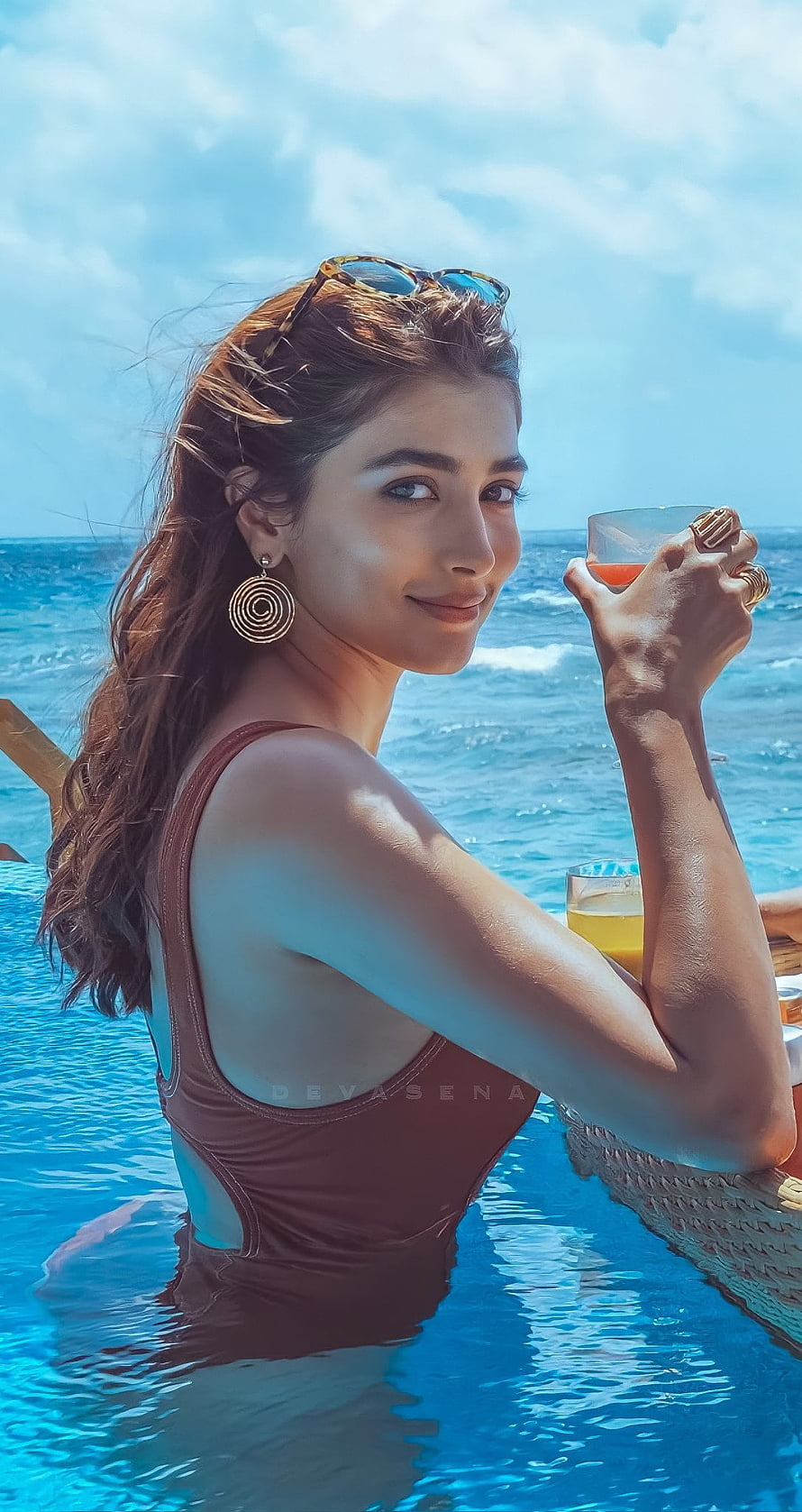 Pooja Hegde in a brown swimsuit at an infinity pool with ocean backdrop HD phone wallpaper