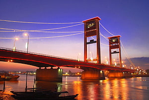 Ampera Bridge in Palembang at Dusk with Red Illumination and River Reflections HD wallpaper