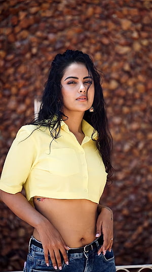 Avika Gor in a cropped yellow shirt and denim jeans against a textured stone wall HD phone wallpaper