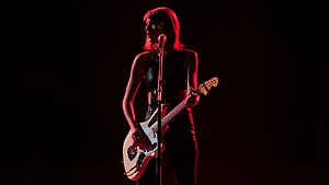 Taylor Swift performing live on stage with electric guitar under dramatic red lighting HD wallpaper