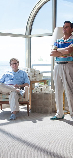Jonah Hill and Leonardo DiCaprio in a sunlit room with stacks of cash HD phone wallpaper
