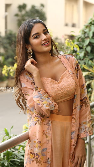 Nidhi Agarwal in a peach floral crop top and matching palazzo set with ornate gold earrings HD phone wallpaper