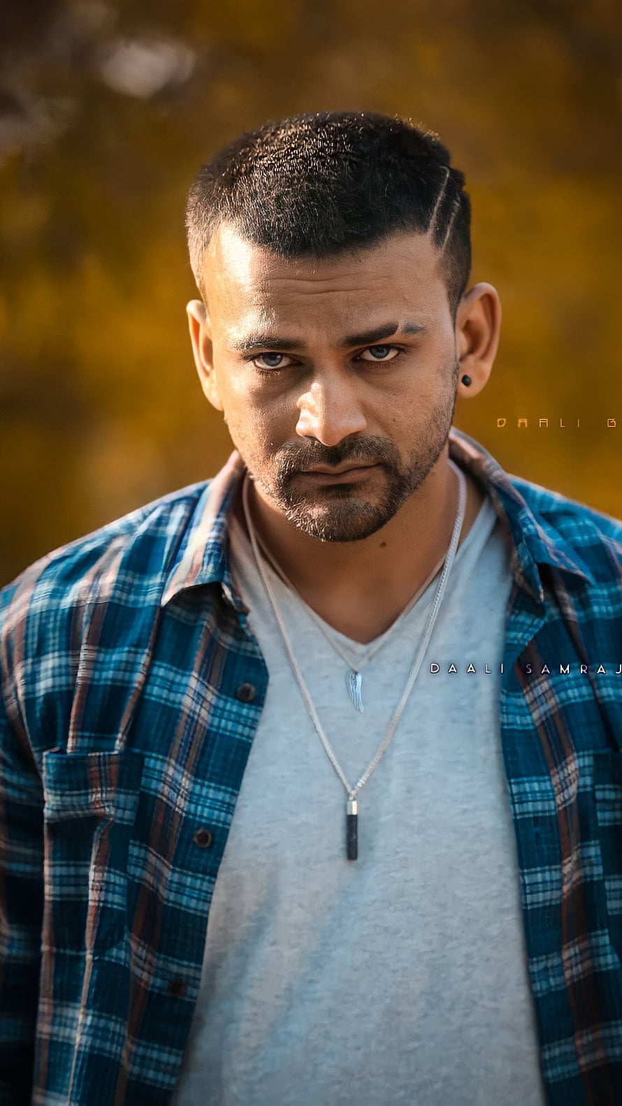 Dhananjay Portrait in Blue Plaid Shirt with Intense Gaze and Autumn Background HD phone wallpaper