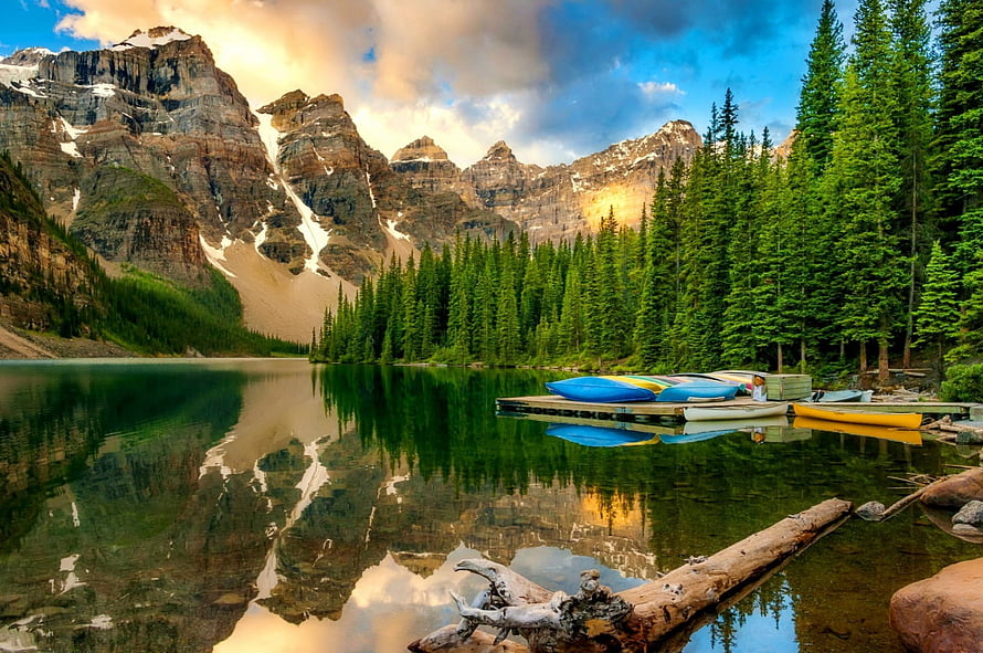 Tranquil Mountain Lake with Canoes and Forest Reflections in the Canadian Rockies HD wallpaper