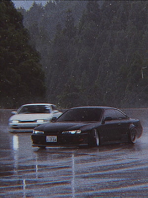 Two JDM sports cars driving on a wet road at dusk with forest backdrop HD phone wallpaper