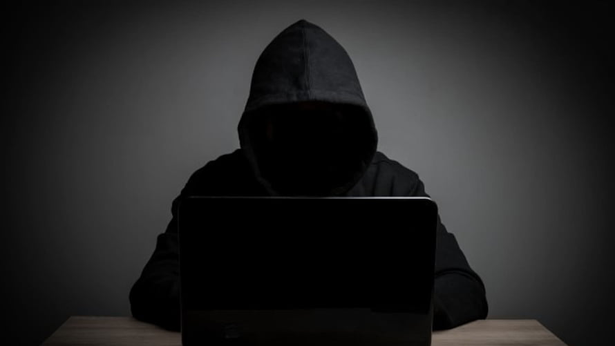 Silhouette of a hooded figure working on a laptop in a dark room HD wallpaper