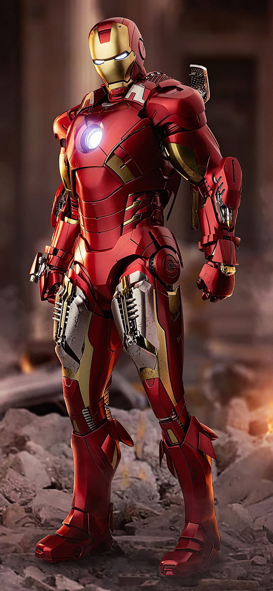 Iron Man Mark 85 Armor Standing in a Ruined Battlefield with Glowing Arc Reactor HD phone wallpaper