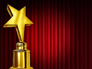 Golden Star Trophy on a Pedestal Against a Deep Red Stage Curtain HD wallpaper