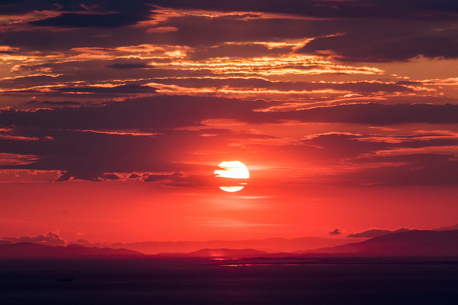 Vibrant Crimson Sunset Over Distant Mountain Ranges and Calm Water HD wallpaper
