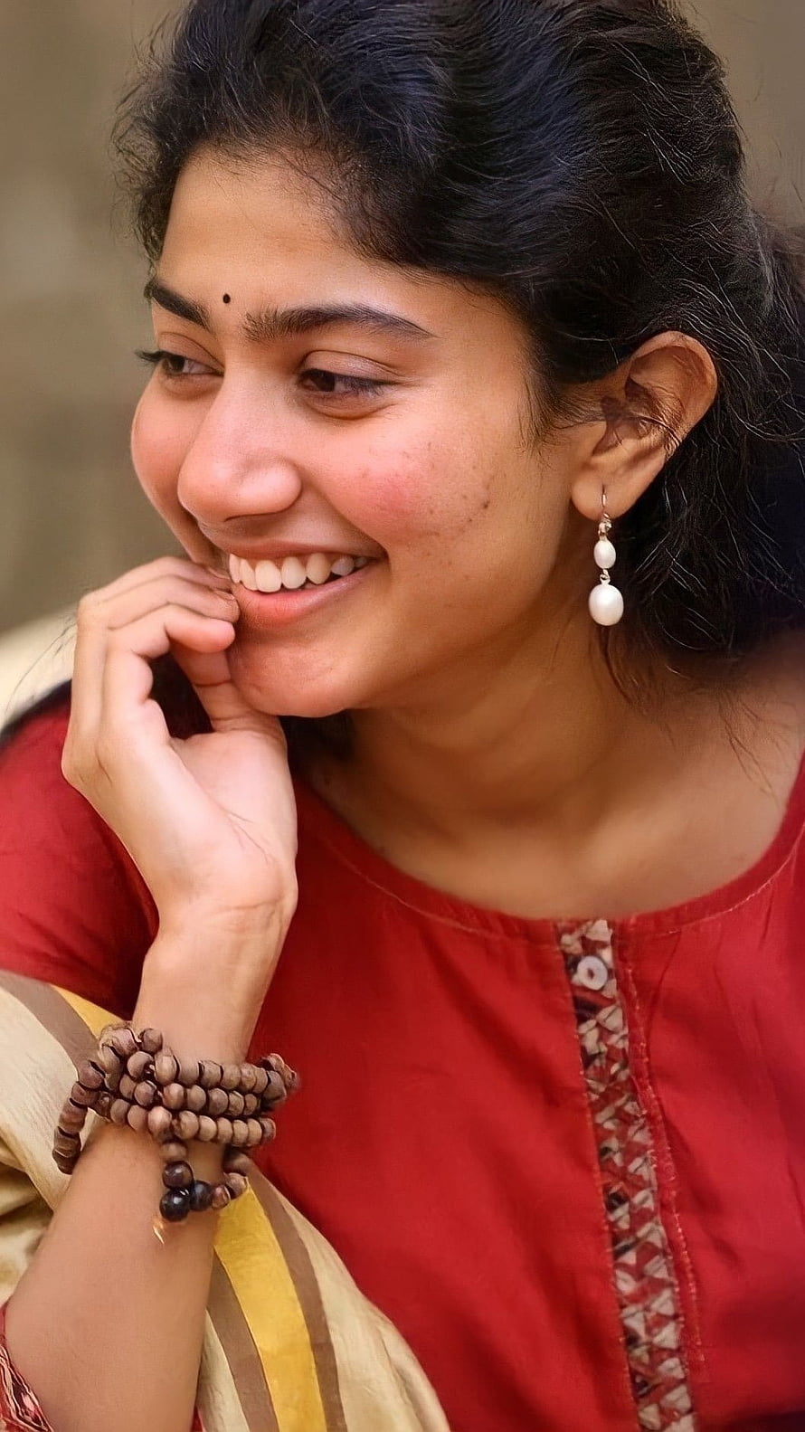 Sai Pallavi smiling portrait in red kurta with pearl earrings and wooden bead bracelets HD phone wallpaper