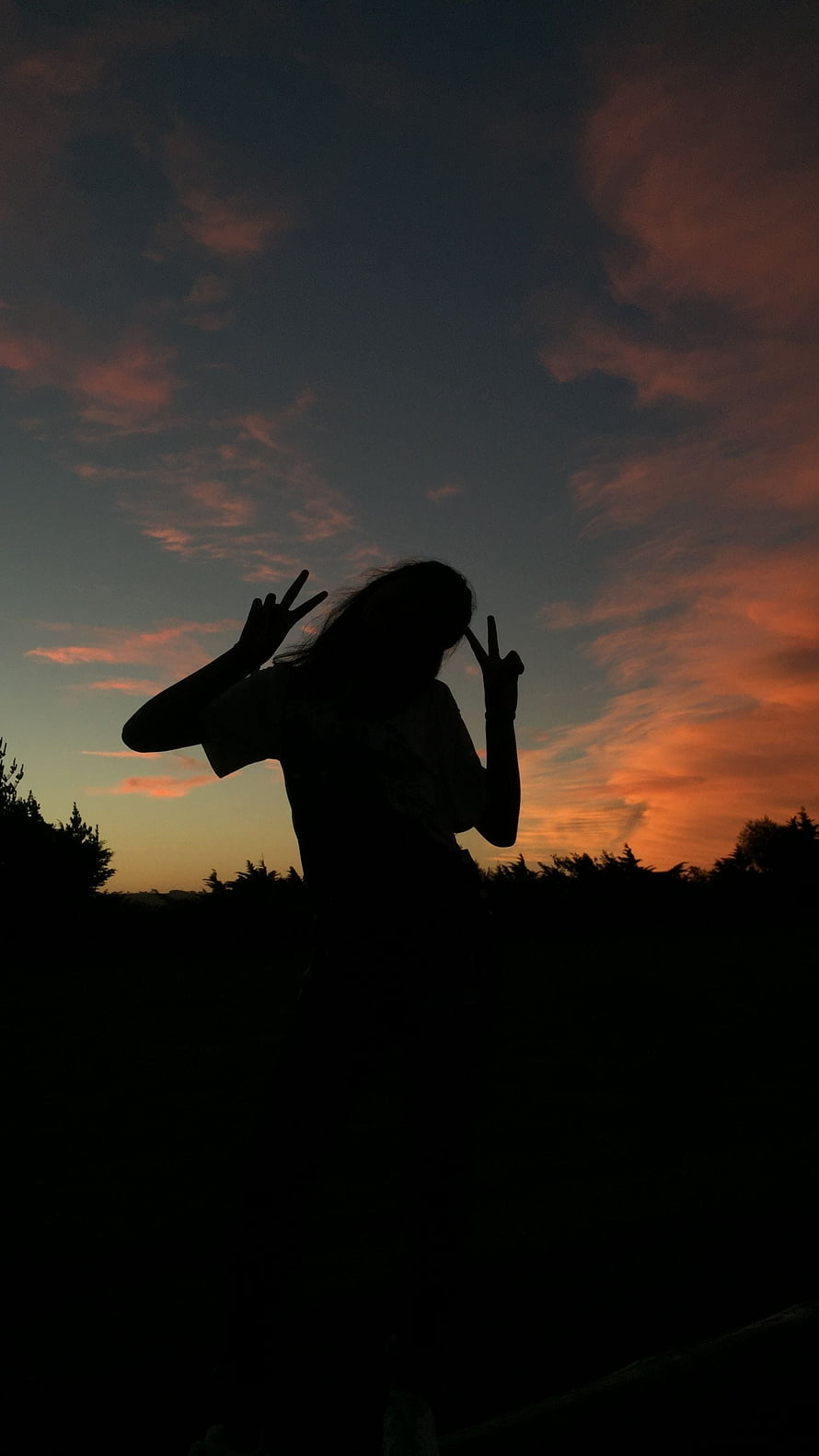 Silhouette of a person making peace signs against a vibrant orange and blue sunset sky HD phone wallpaper