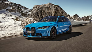 Blue BMW M3 Competition Touring driving on a snowy mountain road HD wallpaper