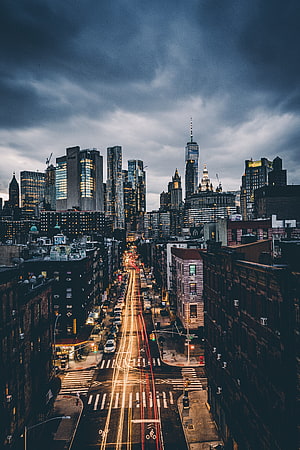Downtown Manhattan Skyline at Dusk with Long Exposure Traffic Trails and Dramatic Storm Clouds HD phone wallpaper