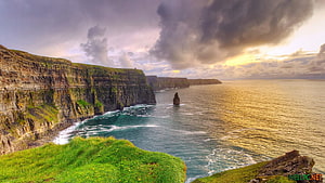 Dramatic Coastal Cliffs and Sea Stack in Ireland Under Stormy Skies HD wallpaper
