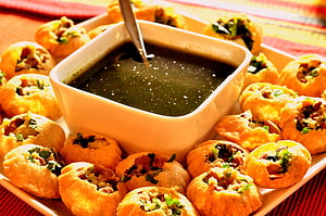 Golden Pani Puri with Spicy Chutney and Fresh Herb Garnish on a White Platter HD wallpaper