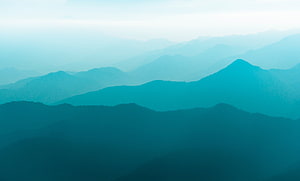 Layered Mountain Range Silhouettes in Teal Mist and Atmospheric Depth HD wallpaper