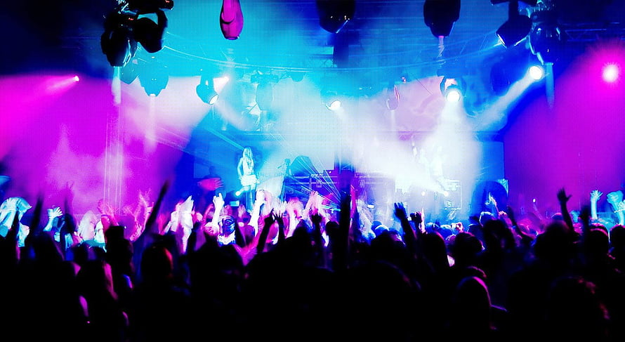 Vibrant nightclub concert scene with purple and blue stage lighting and energetic crowd HD wallpaper
