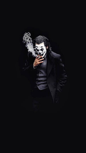Joker in a black suit smoking a cigarette against a dark background HD phone wallpaper