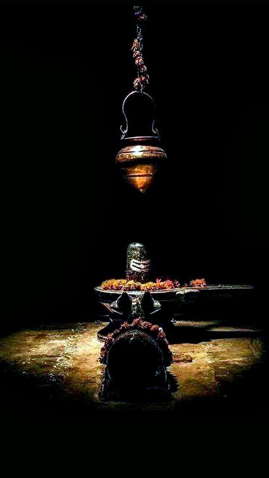 Sacred Shiva Lingam with Hanging Kalash and Floral Offerings in Dramatic Low Light HD phone wallpaper