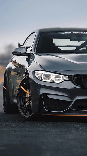 Black BMW M4 Coupe with Orange Accents and Custom Multi-Spoke Wheels HD phone wallpaper