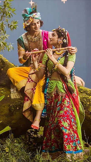 Radha Krishna in Traditional Indian Attire Playing Flute in Lush Garden Setting HD phone wallpaper