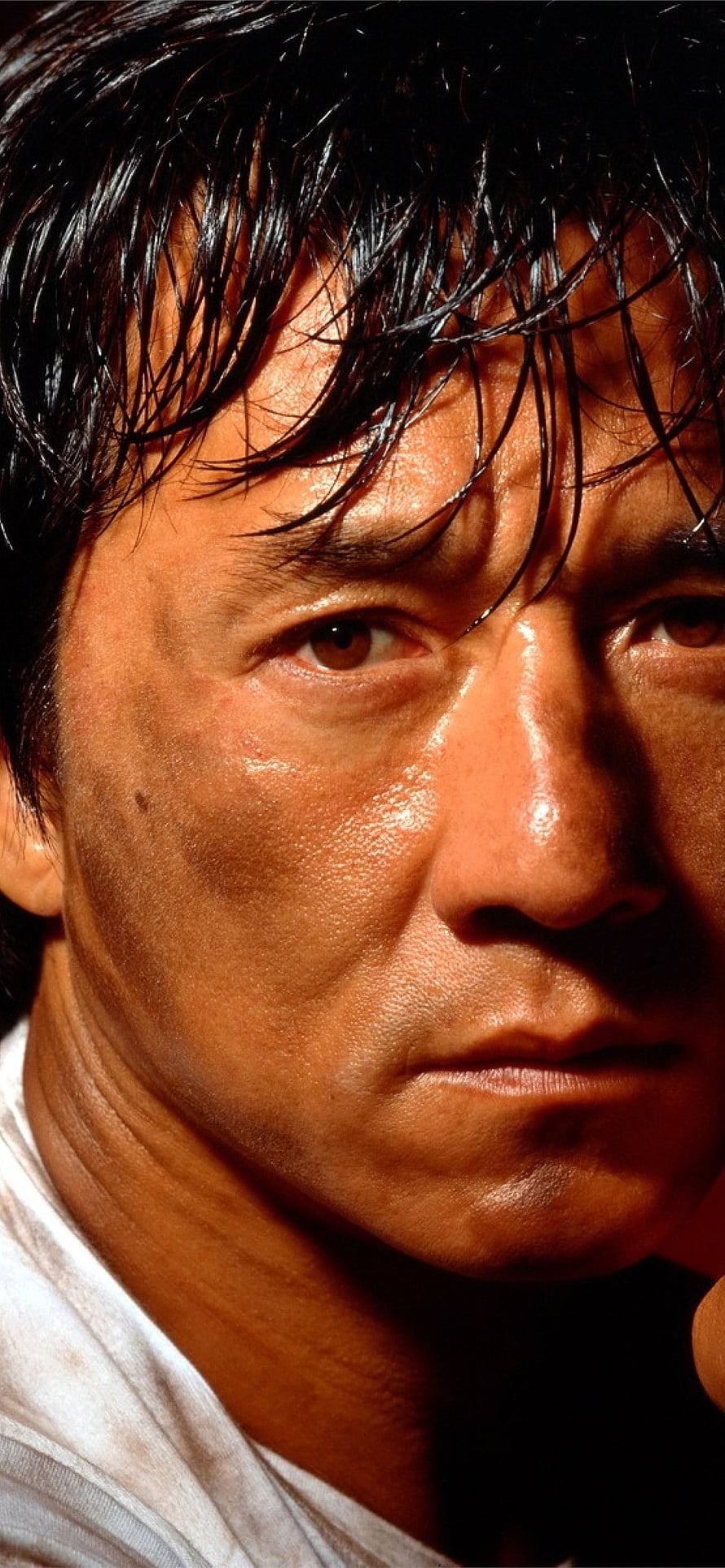 Jackie Chan Intense Close-Up Portrait with Dramatic Lighting and Gritty Expression HD phone wallpaper