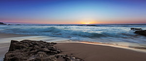 Long Exposure Ocean Sunset with Rolling Waves and Rocky Shoreline HD wallpaper
