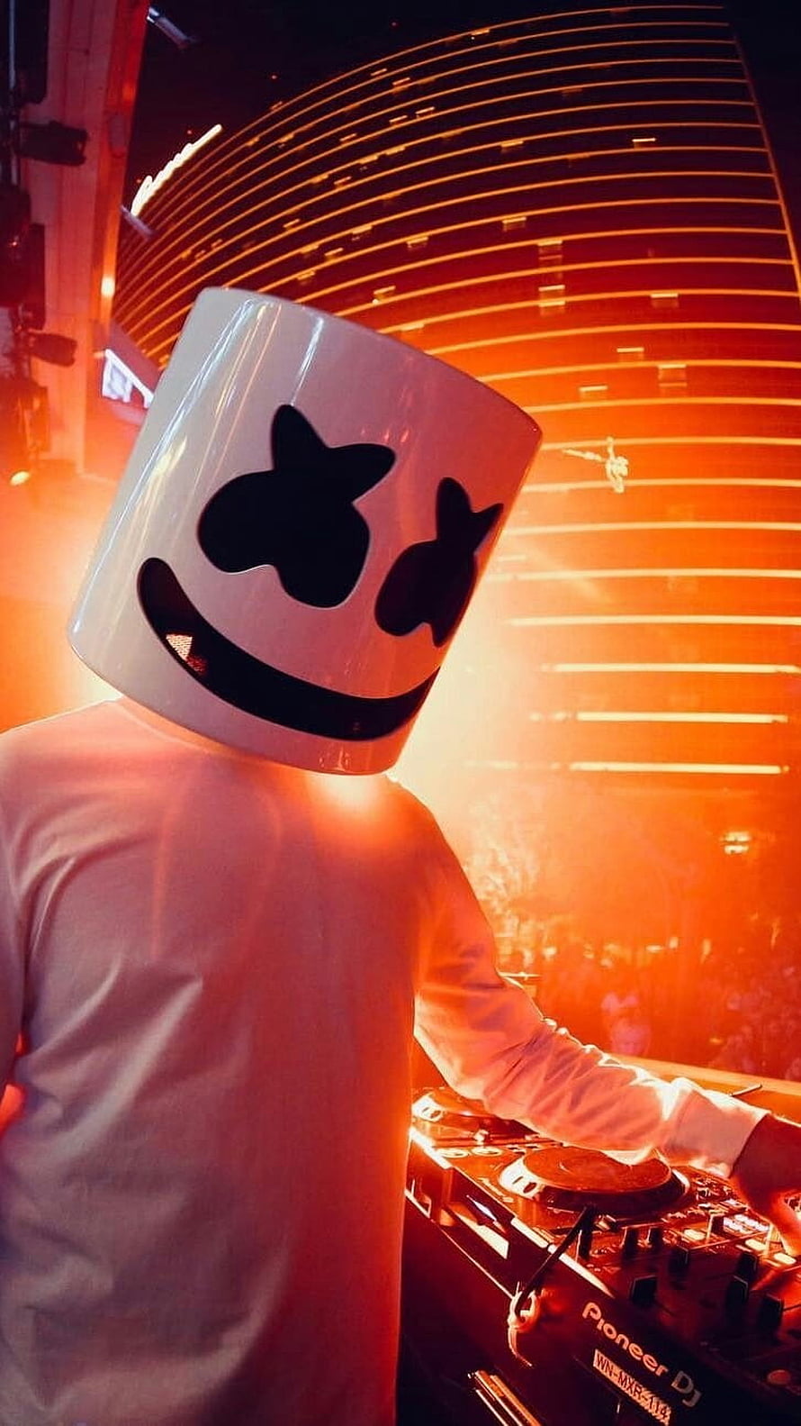 Marshmello DJ performing live on stage with Pioneer equipment under warm orange lighting HD phone wallpaper