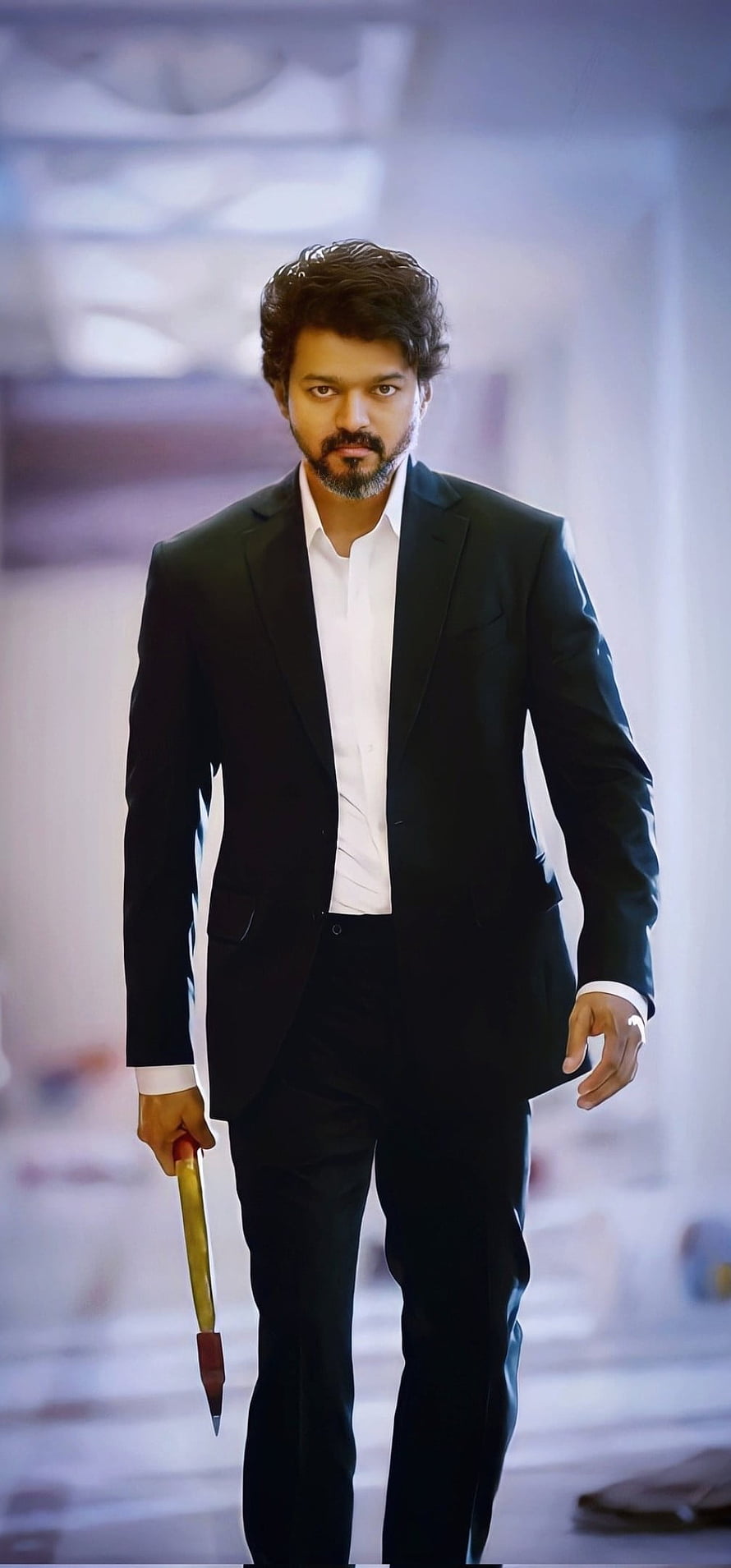 Thalapathy Vijay in a black suit holding a dagger in a cinematic corridor HD phone wallpaper