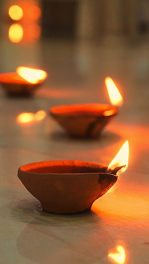 Traditional clay oil lamps glowing warmly during a Diwali celebration HD phone wallpaper