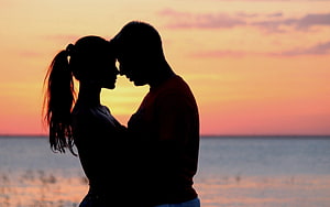 Romantic Couple Silhouette Embracing at Sunset by the Ocean HD wallpaper