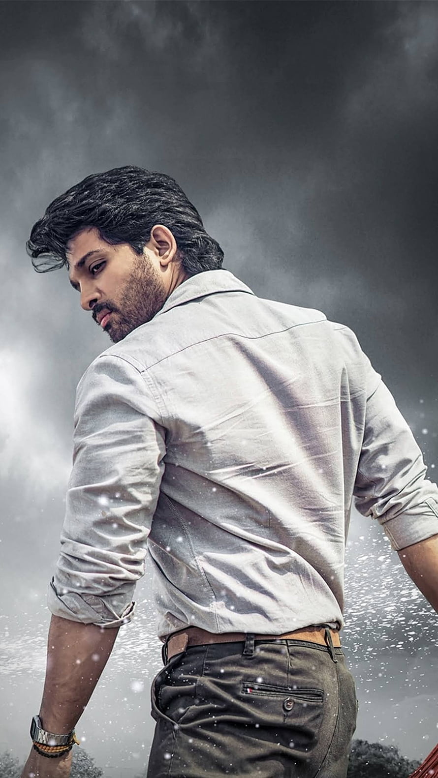 Allu Arjun in a light shirt against a dramatic stormy sky with falling snow HD phone wallpaper