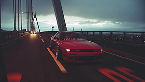 Red Nissan Skyline R32 drifting on a suspension bridge at dusk with headlights on HD wallpaper