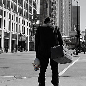 Joker from The Dark Knight walking through a city street carrying a clown mask and duffel bag HD phone wallpaper