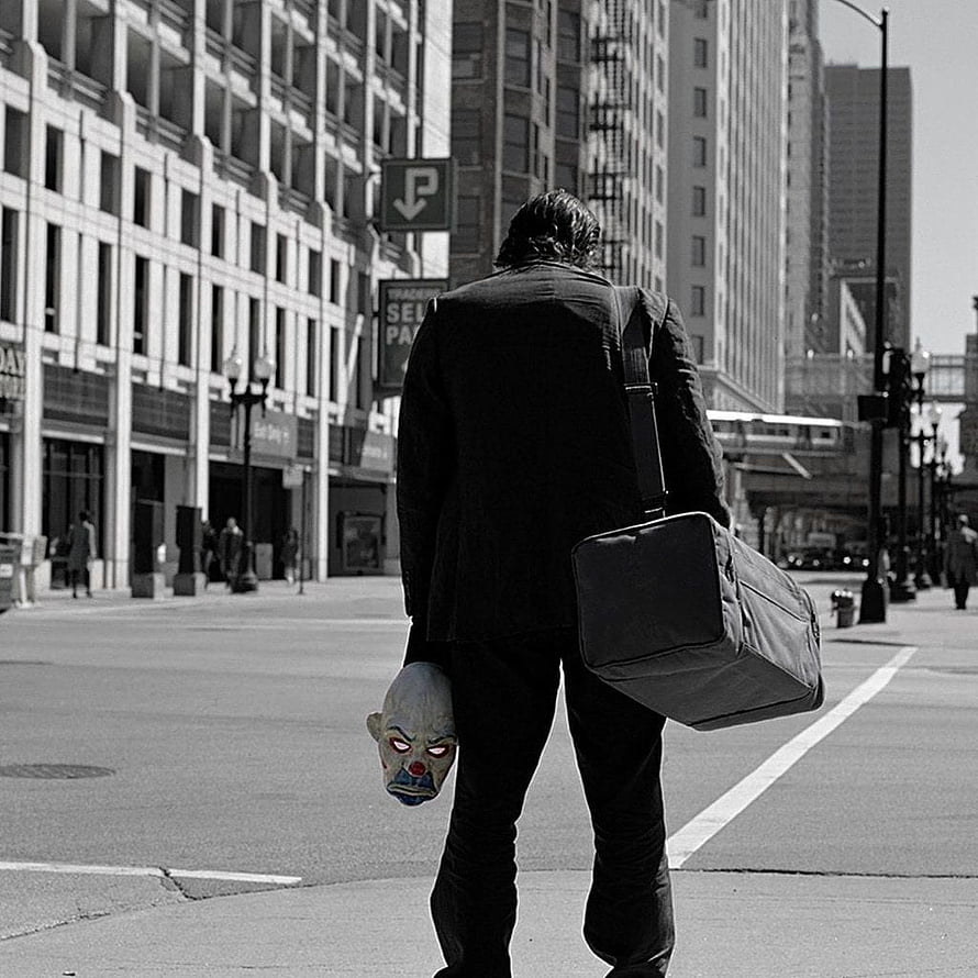 Joker from The Dark Knight walking through a city street carrying a clown mask and duffel bag HD phone wallpaper
