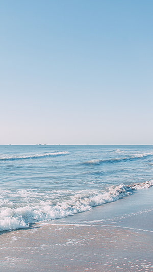 Pastel Blue Ocean Waves Rolling onto a Serene Sandy Beach Under a Clear Sky HD phone wallpaper