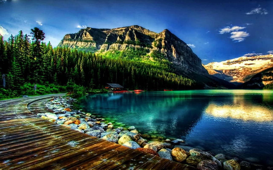 Serene Mountain Lake with Wooden Boardwalk and Pine Forest Under Dramatic Sky HD wallpaper