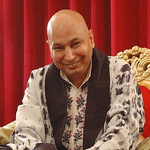Portrait of a smiling bald man in traditional embroidered attire seated before a red curtain, Guruji Chatarpur - Guruji Bade Mandir Timings - - teahub.io HD phone wallpaper