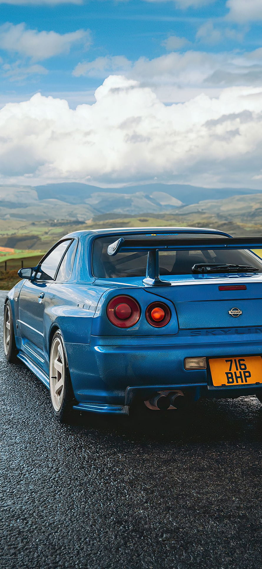Blue Nissan Skyline GT-R R34 Rear View on Mountain Road with Dramatic Sky HD phone wallpaper
