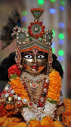 Ornate Krishna Murti with Peacock Feather Crown and Marigold Garland HD phone wallpaper